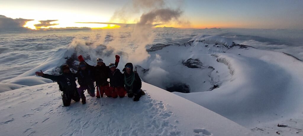 Climbers celebrating at the summit of Cotopaxi at sunrise with crater view